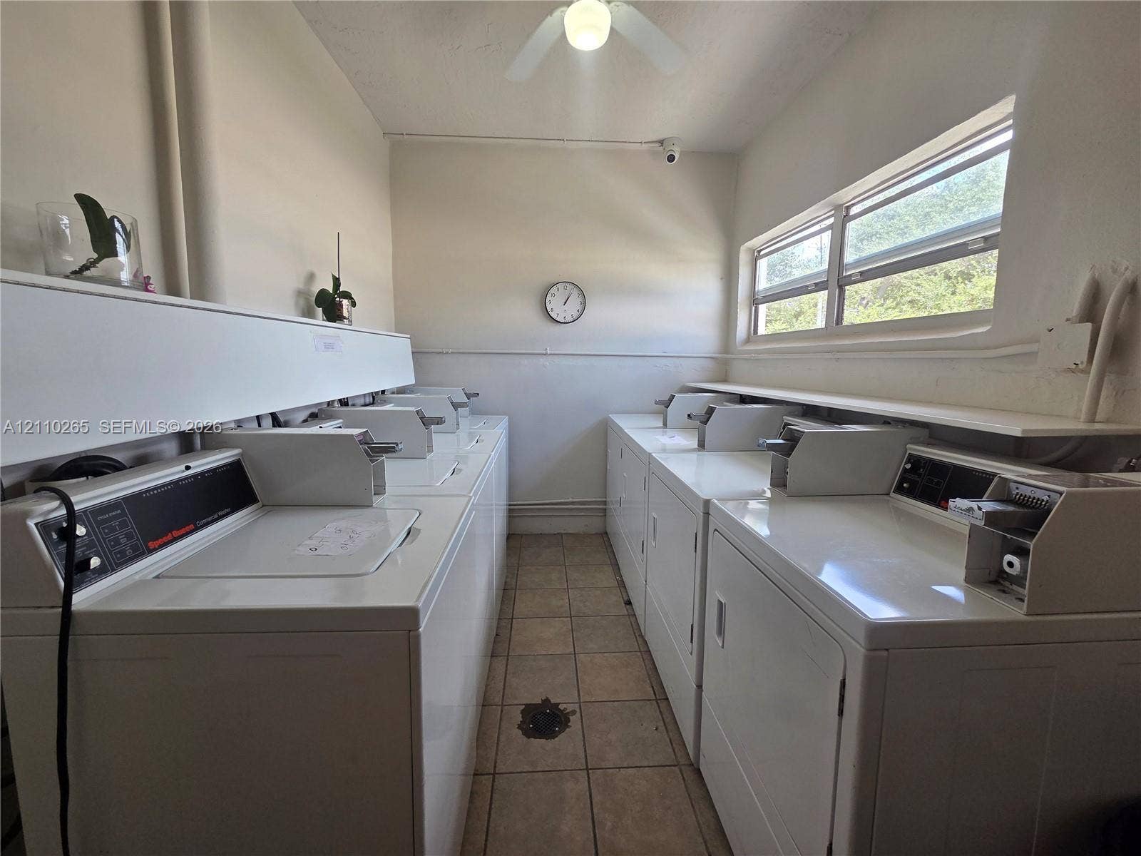 415 NE 2nd Street, #106, Hallandale Beach, Hallandale Beach, FL 33009 Utility space featuring ceramic tile flooring, horizontal window exposure, mounted ceiling fan, and built-in shelving