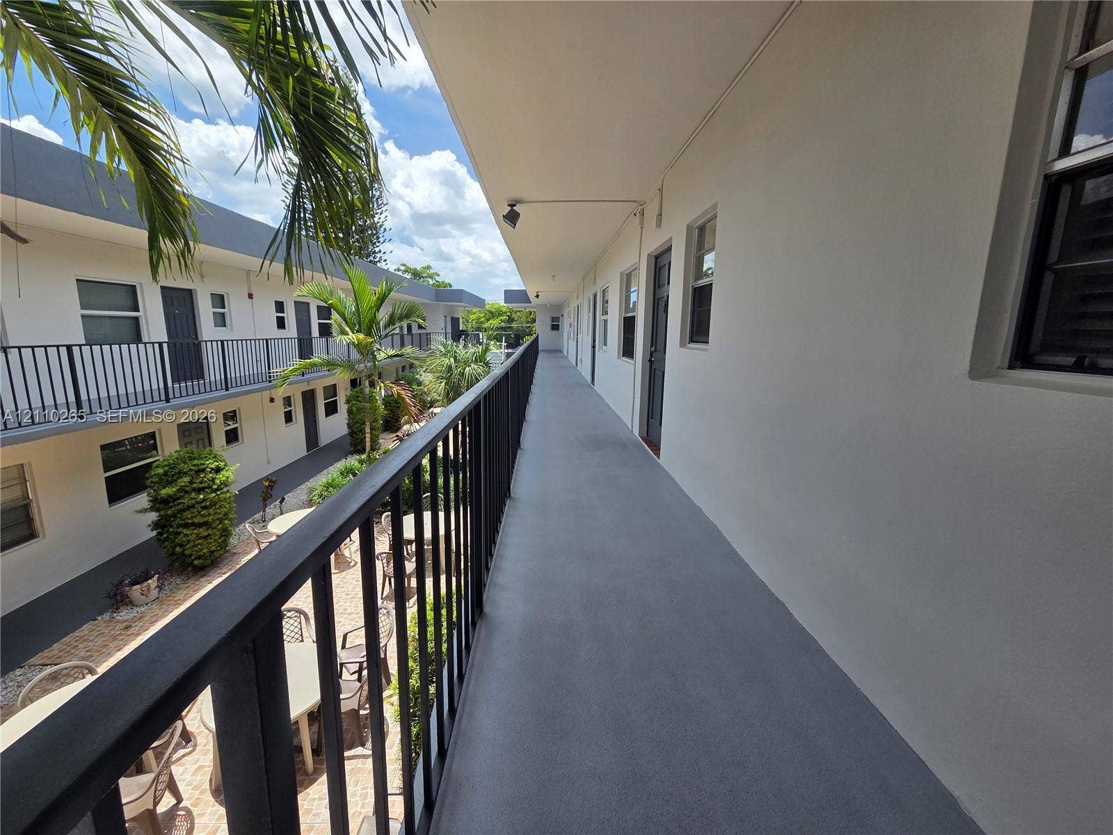 415 NE 2nd Street, #106, Hallandale Beach, Hallandale Beach, FL 33009 Exterior corridor featuring a smooth concrete walkway, black metal railings, and recessed ceiling lighting