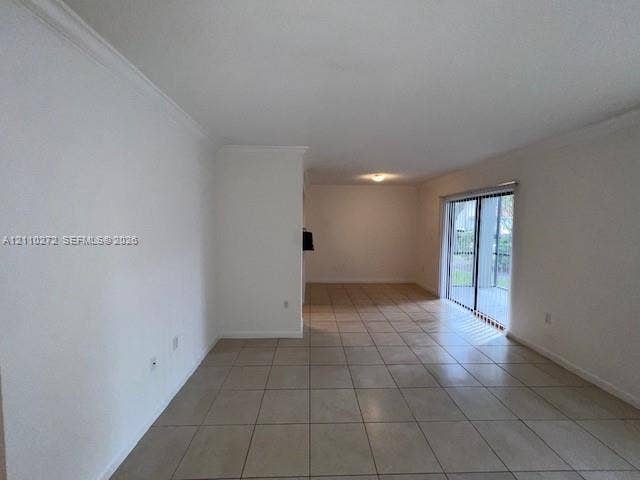 Open-concept interior featuring neutral ceramic tile flooring, crown molding, and a sliding glass door providing external access