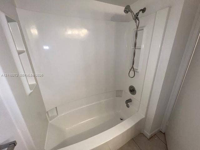 Bathtub and shower combination featuring a glossy white surround, integrated shelving niches, and a polished metallic handheld shower fixture