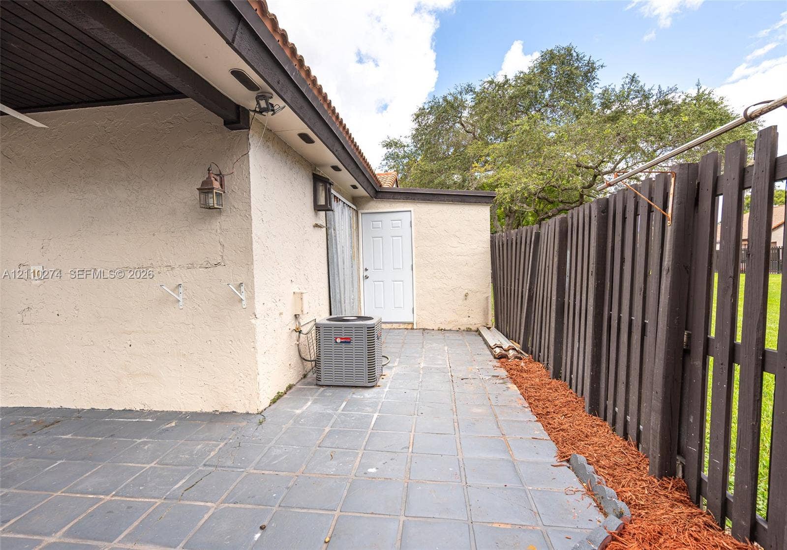 14955 SW 49th Lane, #5E, Miami, FL 33185 Covered patio featuring tiled flooring, stucco exterior walls, and a wood-slat privacy fence