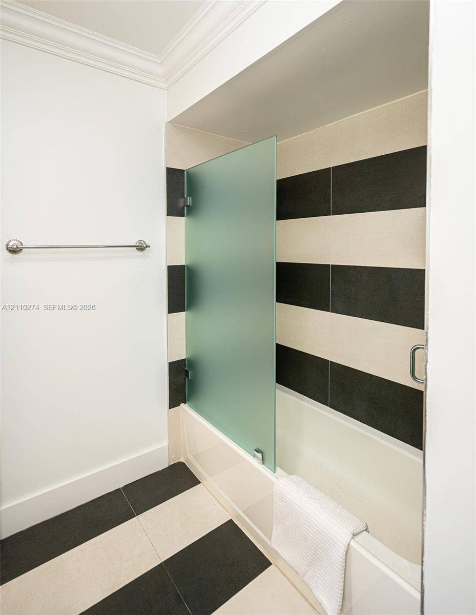 14955 SW 49th Lane, #5E, Miami, FL 33185 Bathtub featuring a frosted glass panel, high-contrast horizontal tile wall surround, and large-format two-tone floor tiling