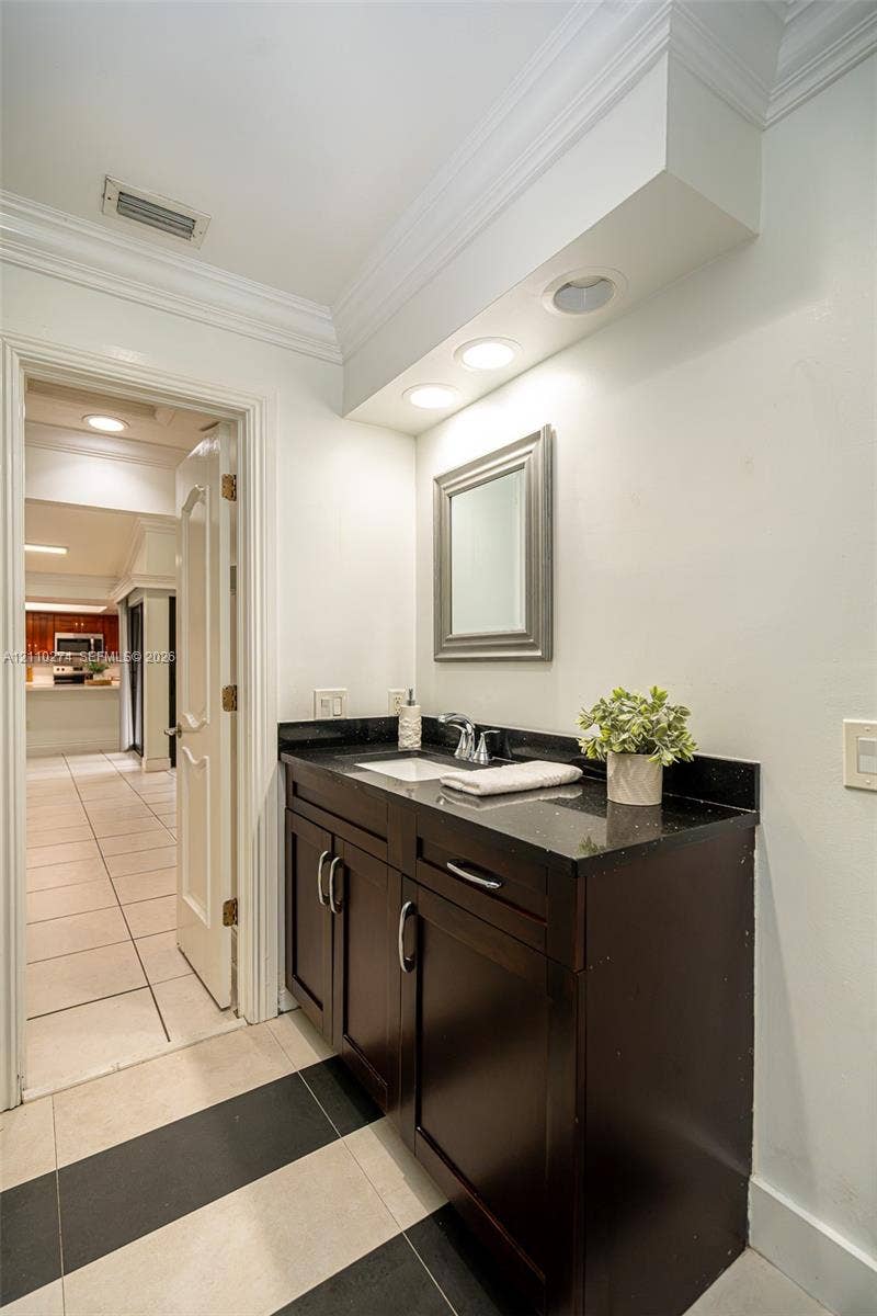 14955 SW 49th Lane, #5E, Miami, FL 33185 Dark wood vanity featuring a polished stone countertop, integrated sink, recessed lighting, and crown molding