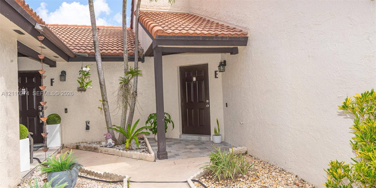 14955 SW 49th Lane, #5E, Miami, FL 33185 Exterior entryway featuring a stucco facade, clay tile roof, dark-finished entry doors, and a stone-paver walkway