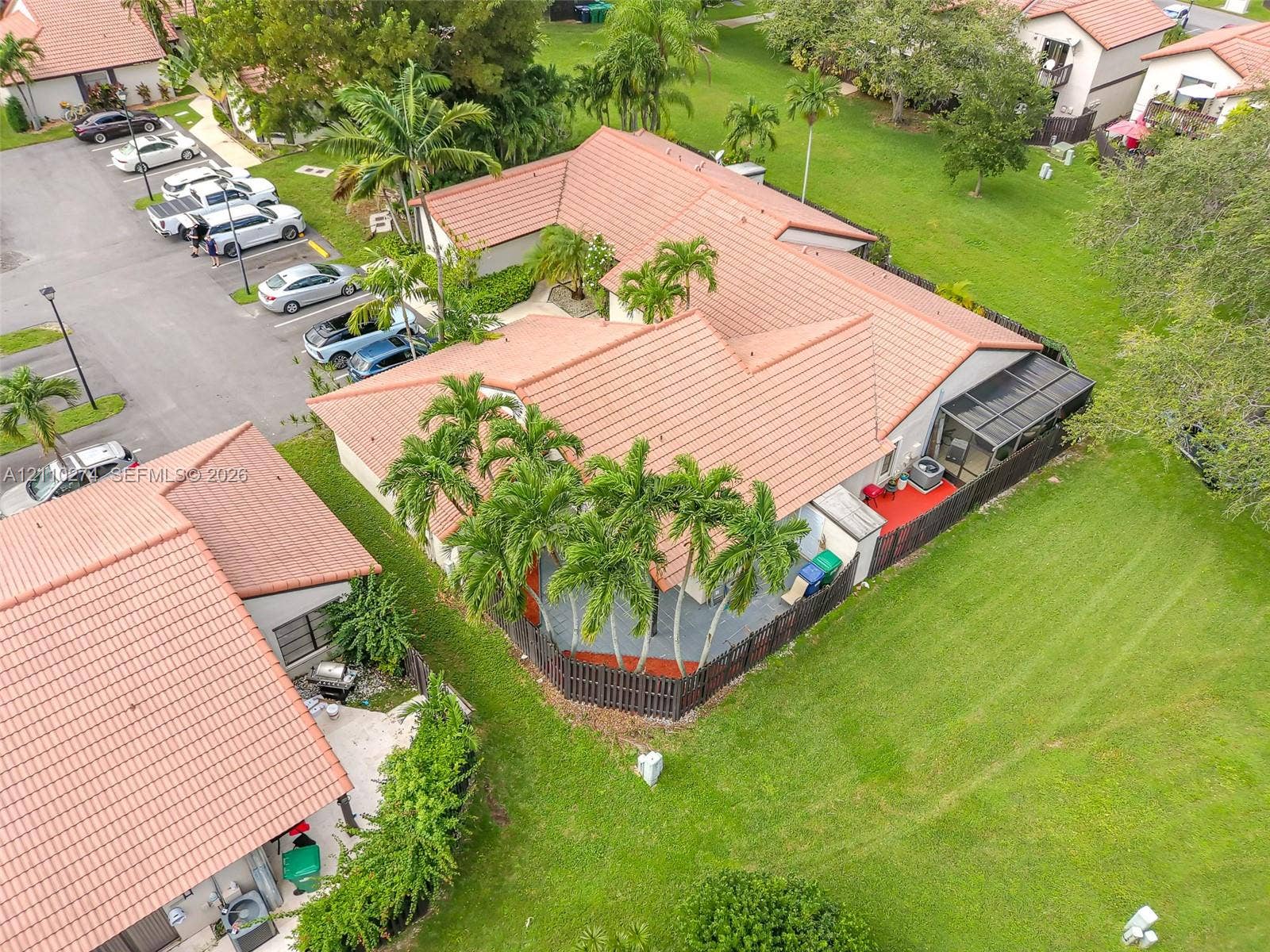 14955 SW 49th Lane, #5E, Miami, FL 33185 Aerial perspective of a residence featuring a clay tile roof, a screened-in patio, and fenced-in hardscaped areas surrounded by manicured grounds