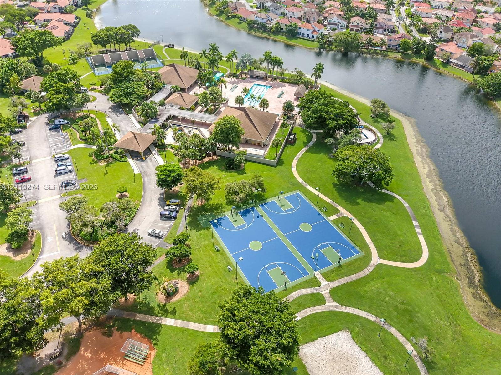 14955 SW 49th Lane, #5E, Miami, FL 33185 Community recreational area featuring dual basketball courts, a swimming pool, winding paved pathways, and waterfront access