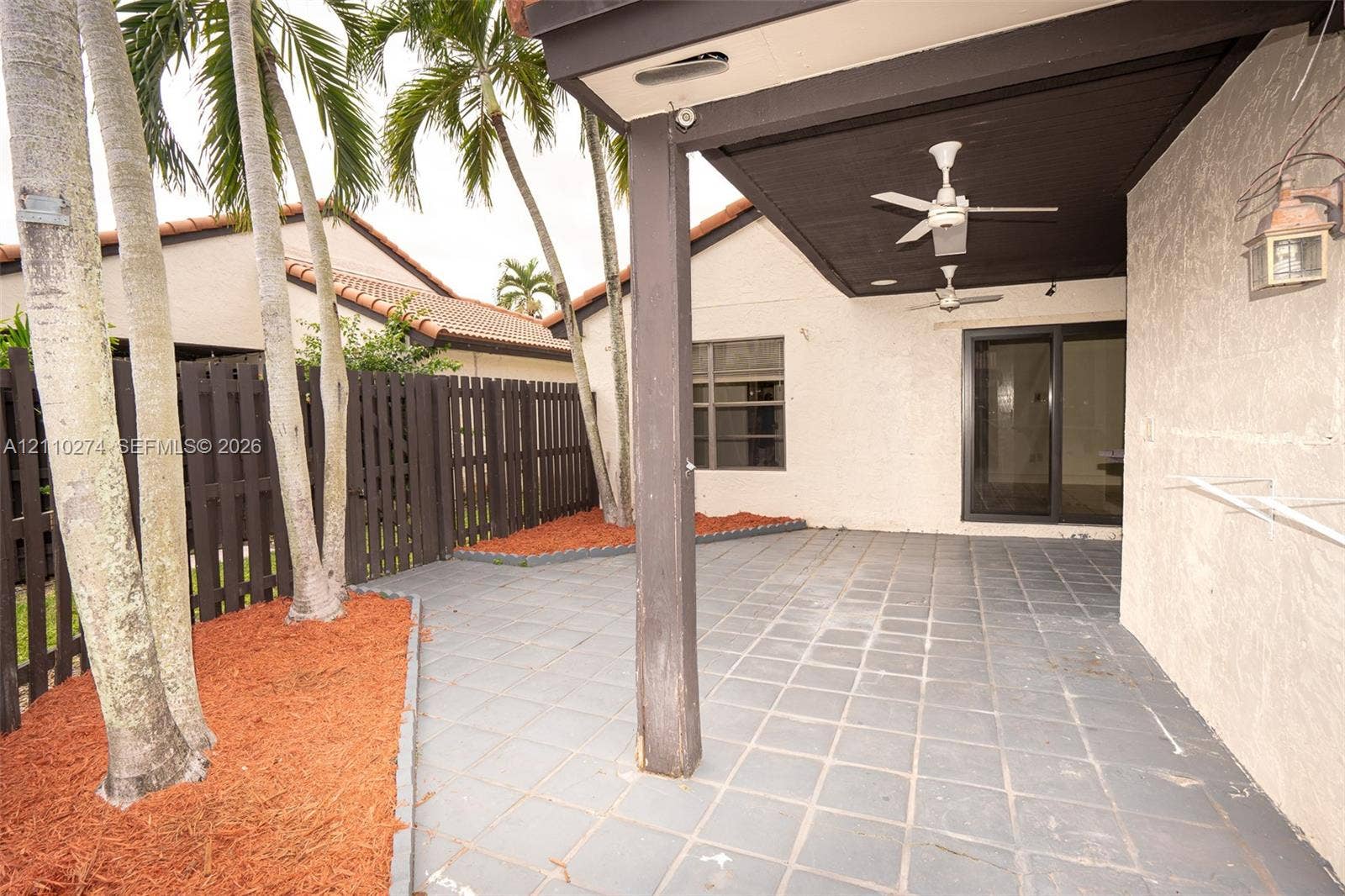 14955 SW 49th Lane, #5E, Miami, FL 33185 Covered patio with tile flooring, ceiling fans, integrated wall-mounted exterior lighting, and wood-slat fencing