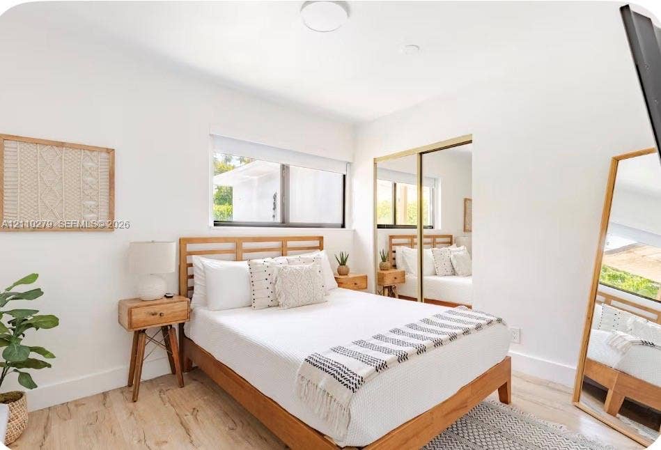 Bright room featuring wood-finish flooring, a horizontal window, and floor-to-ceiling mirrored closet doors