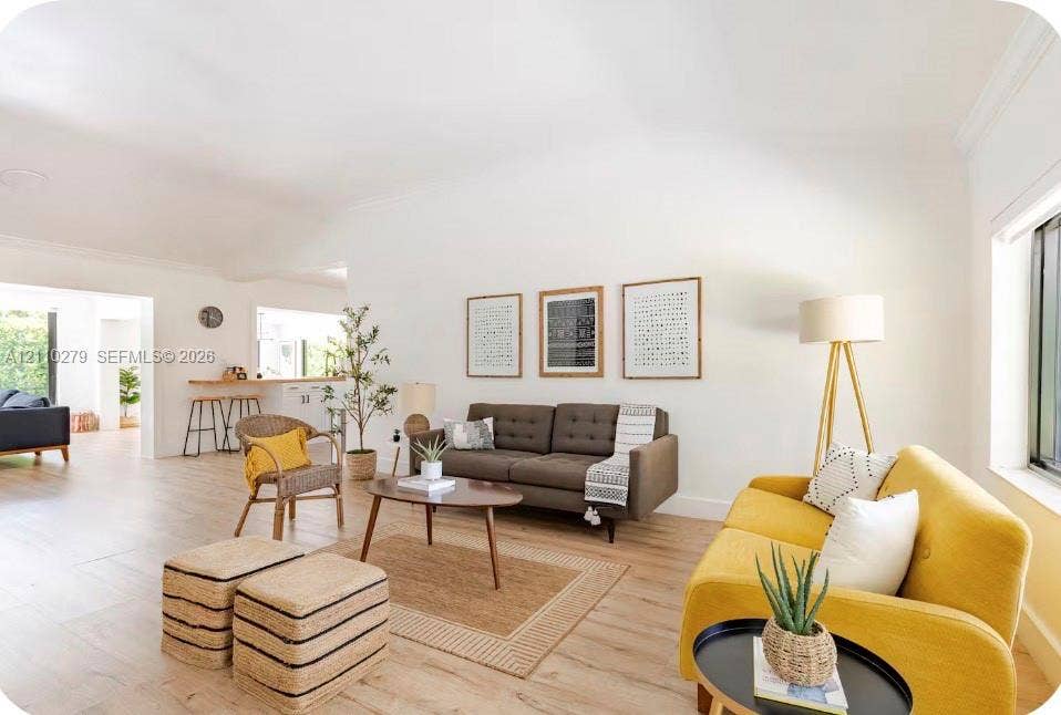 Open-concept interior featuring high vaulted ceilings, wood-finish flooring, and crown molding