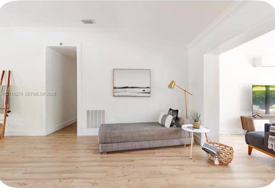 Light-toned wood-finish flooring, crisp white walls, and decorative crown molding
