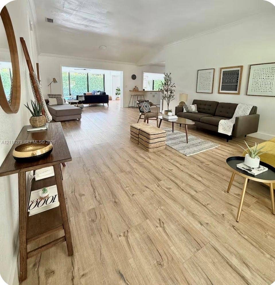 Open-concept interior featuring wood-finish flooring, vaulted ceilings, and floor-to-ceiling glass wall panels