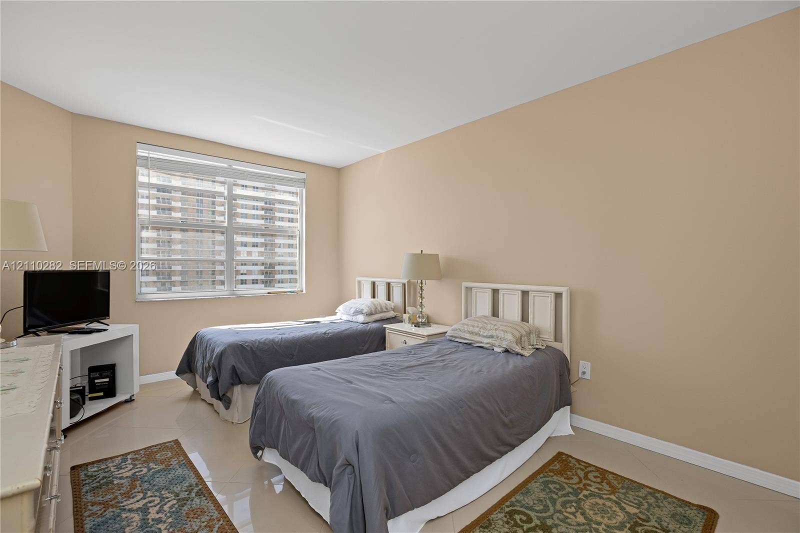 Neutral-toned room featuring large windows with fitted horizontal blinds and polished tile flooring