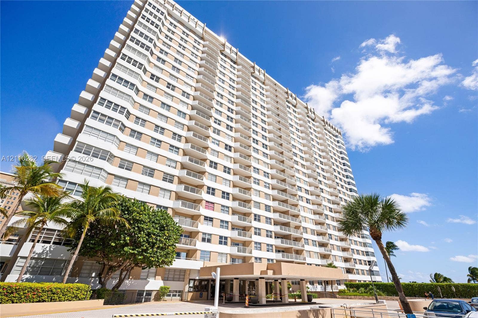 High-rise residential exterior featuring a multi-story facade, integrated private balconies, and a covered porte-cochre entry