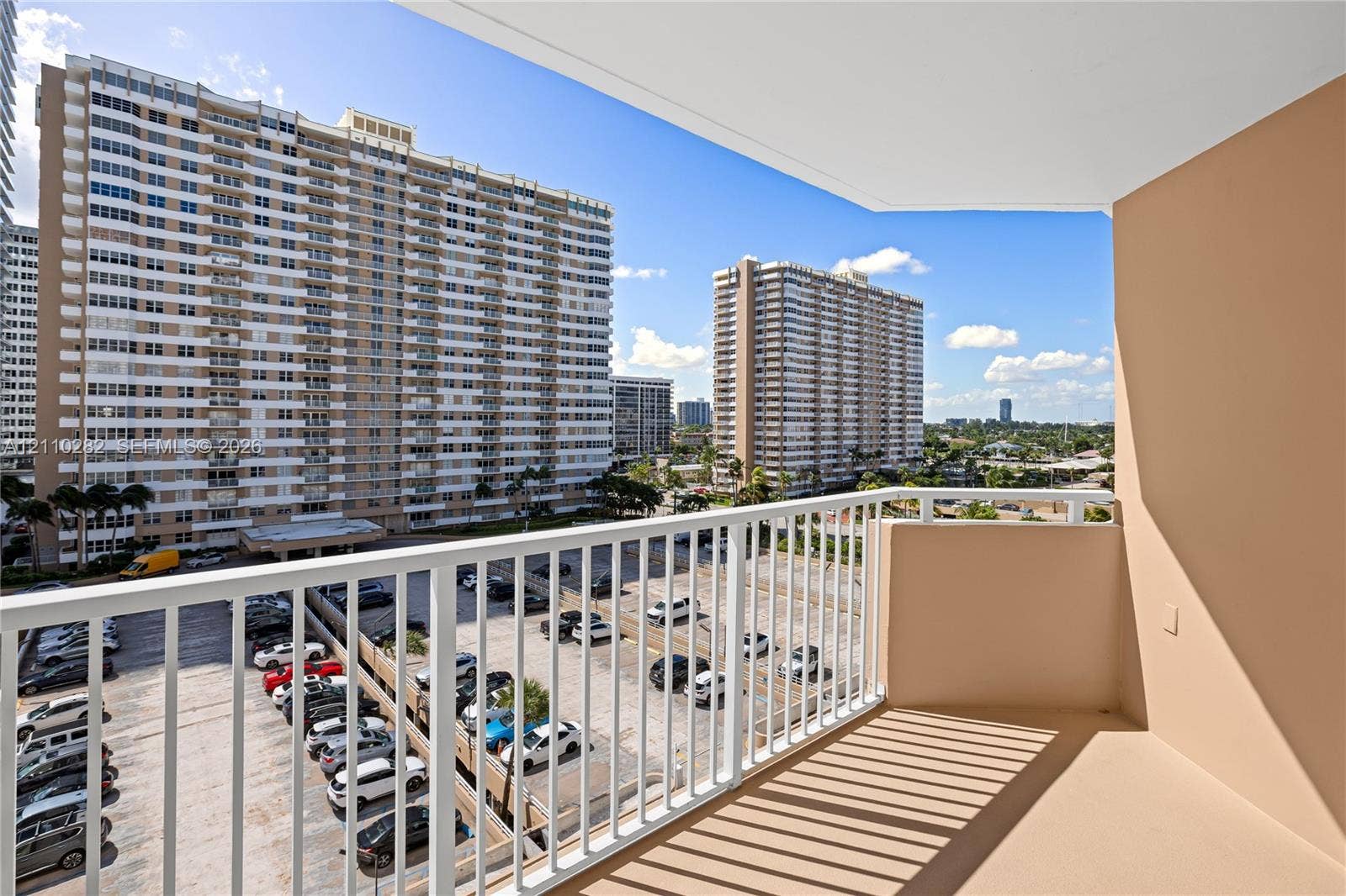 Covered balcony featuring white vertical railings and concrete flooring