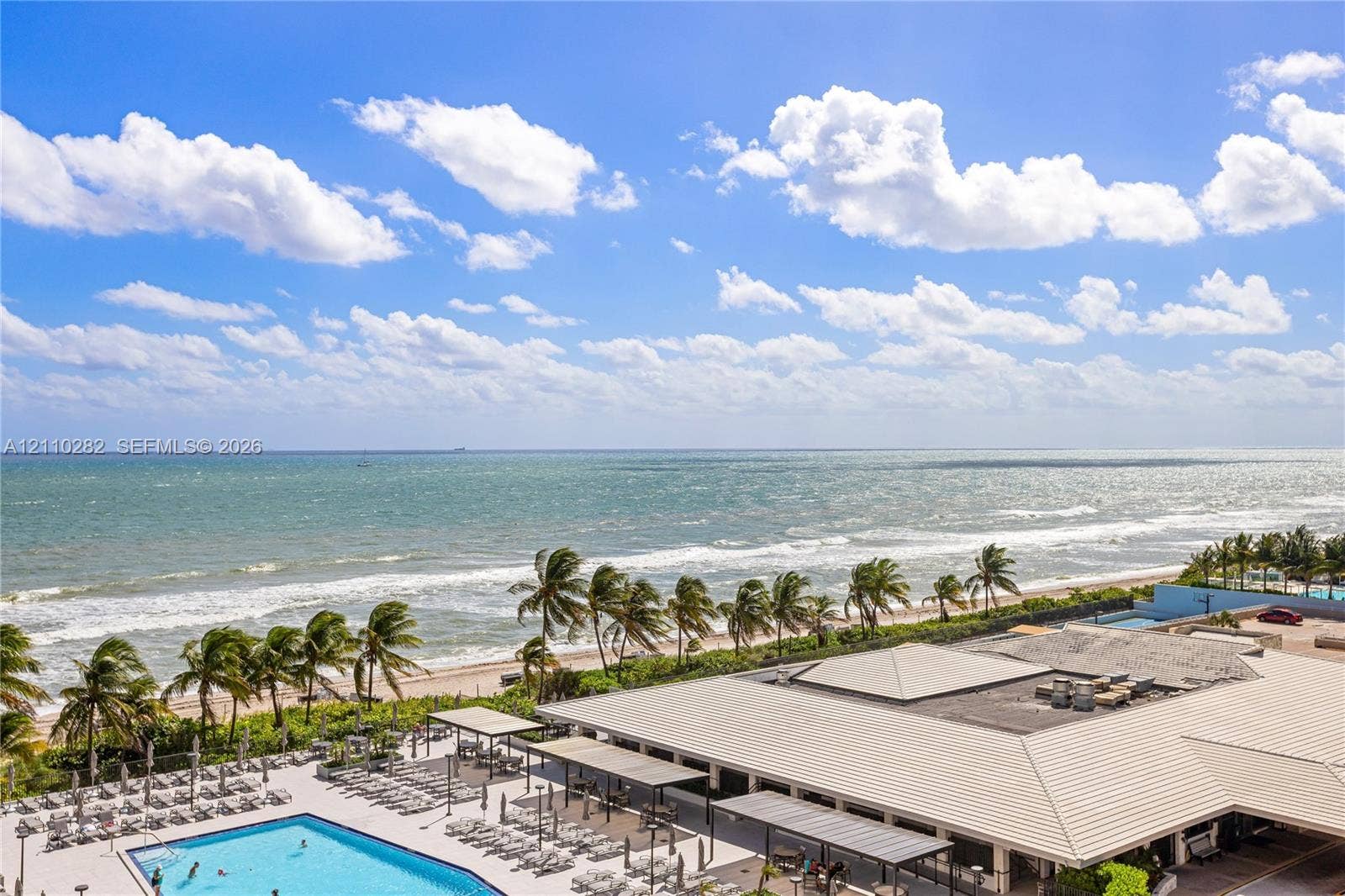 Outdoor swimming pool, paved pool deck, shaded patio structures, and direct coastal proximity