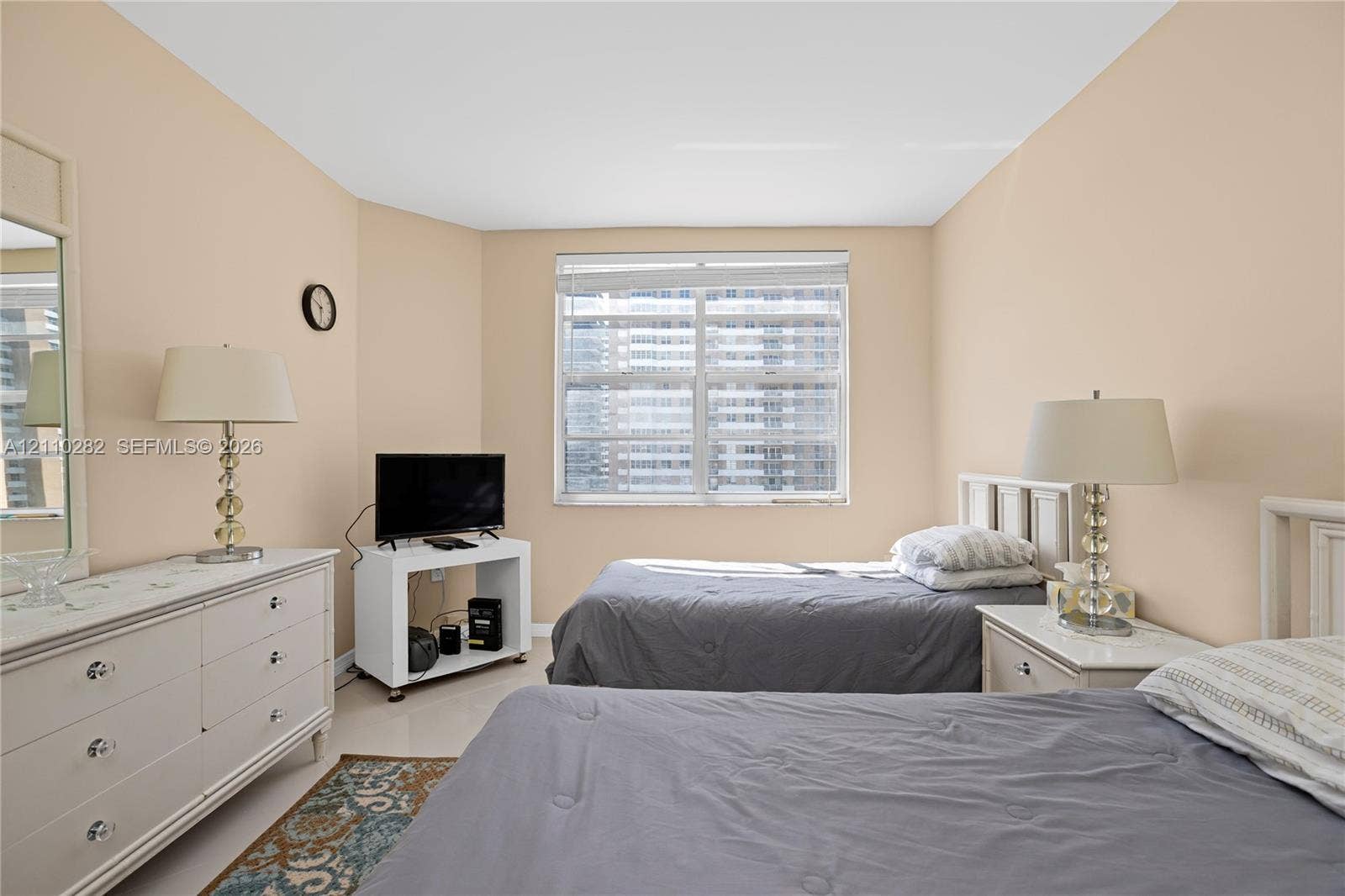 Neutral-toned interior space featuring a large window with horizontal blinds and polished tile flooring