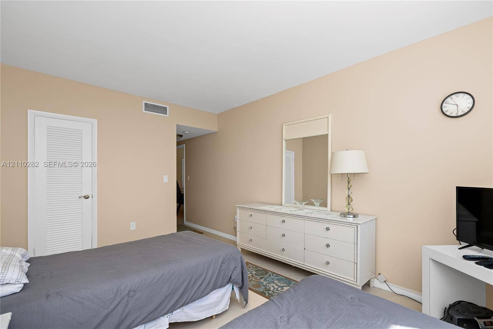 Neutral-toned interior space featuring a louvered-panel closet door and solid surface flooring