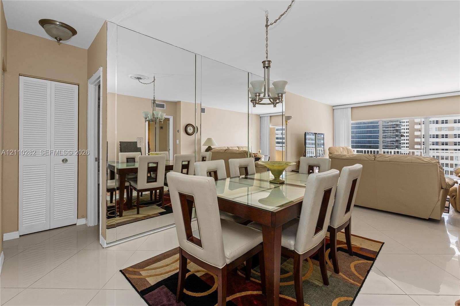Full-wall mirror accent, polished tile flooring, ceiling-mounted multi-light fixture, and bi-fold closet doors