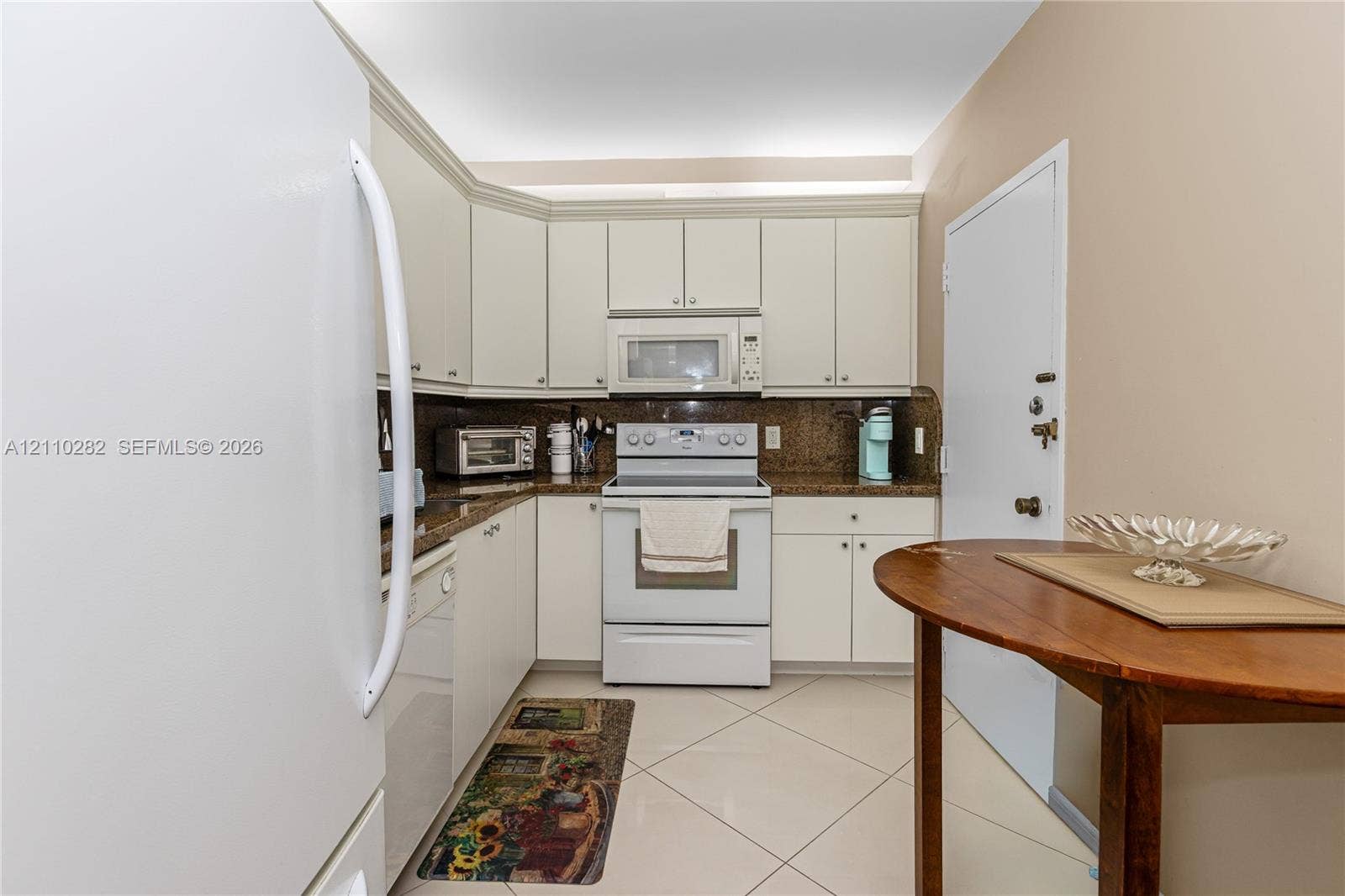 Kitchen featuring white cabinetry, stone-finish countertops, tile flooring, and integrated white appliances