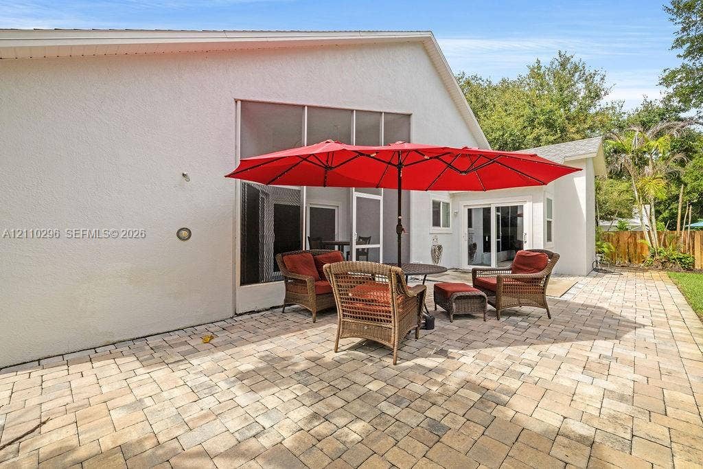 Exterior patio featuring stone-paver flooring, a screened-in enclosure, and glass sliding door access