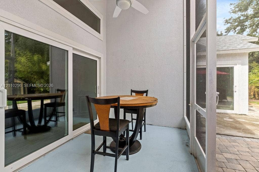 Screened-in patio featuring a ceiling fan, transom windows, sliding glass doors, and paver hardscaping