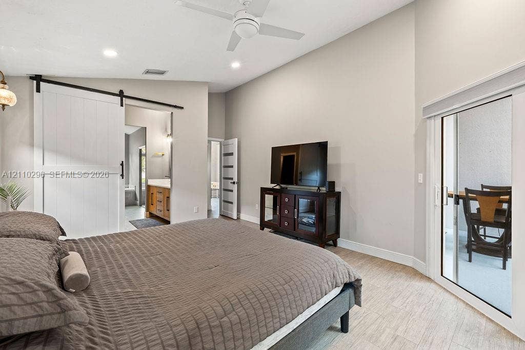 Vaulted ceilings, sliding barn door, neutral interior paint, tile flooring, and glass sliding door