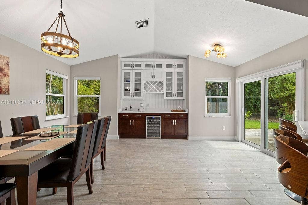 Vaulted ceilings featuring custom built-in cabinetry, an integrated wine refrigerator, tile flooring, and sliding glass doors