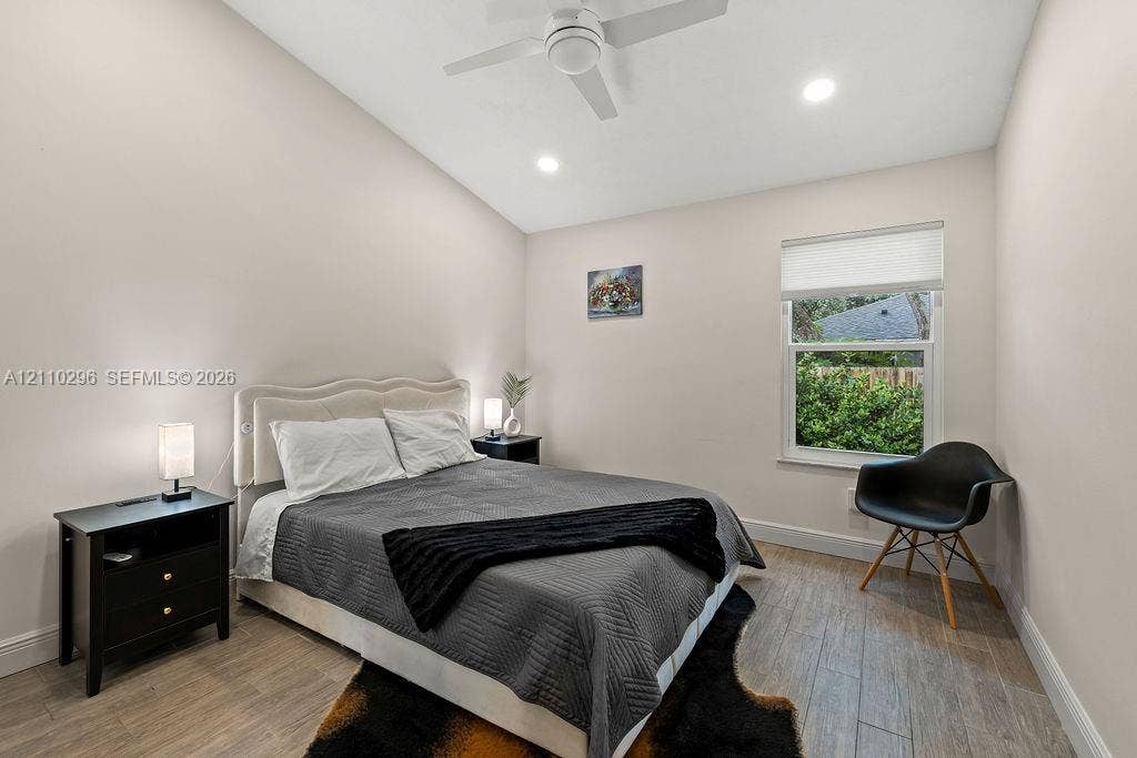 Vaulted ceiling featuring a central cooling fan and recessed lighting, paired with wood-finish flooring and a window with a fitted roller shade