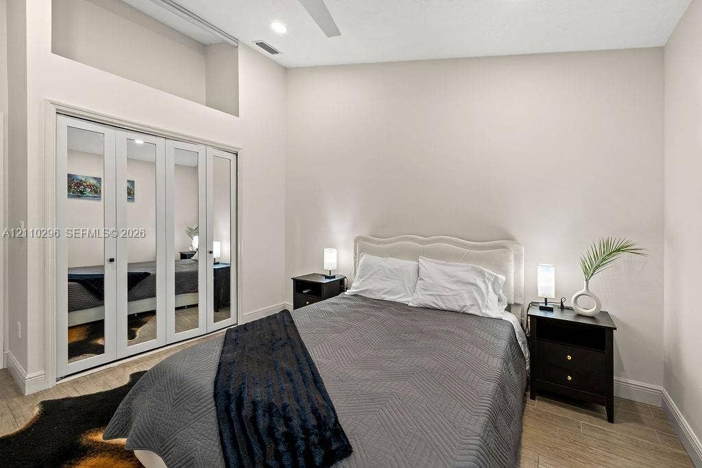 High ceilings with recessed lighting, wood-finish flooring, and a multi-panel mirrored closet with integrated architectural alcove