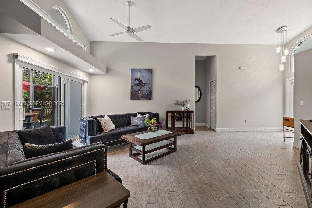 Vaulted ceilings featuring recessed lighting, ceramic wood-finish flooring, sliding glass doors, arched clerestory windows, and modern pendant lighting