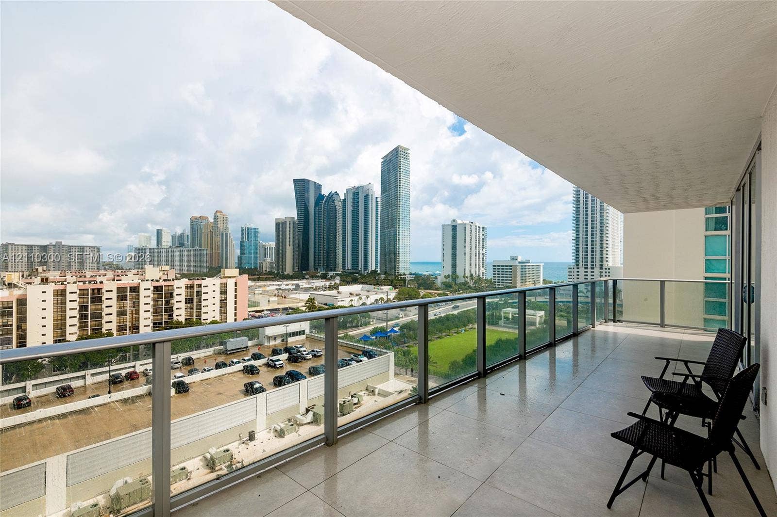 Covered balcony featuring large-format tile flooring and a glass-paneled railing