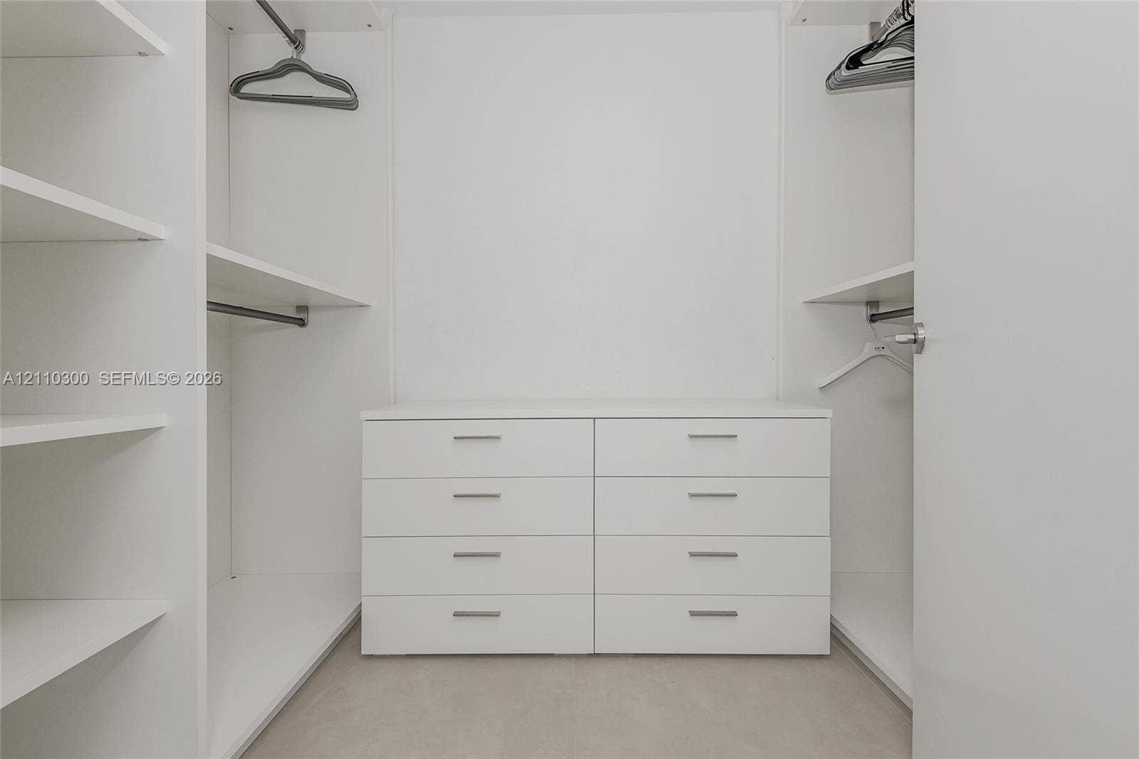 Master Bedroom. Built-in closet featuring white cabinetry, eight integrated storage drawers, adjustable shelving units, and dual metal hanging rods