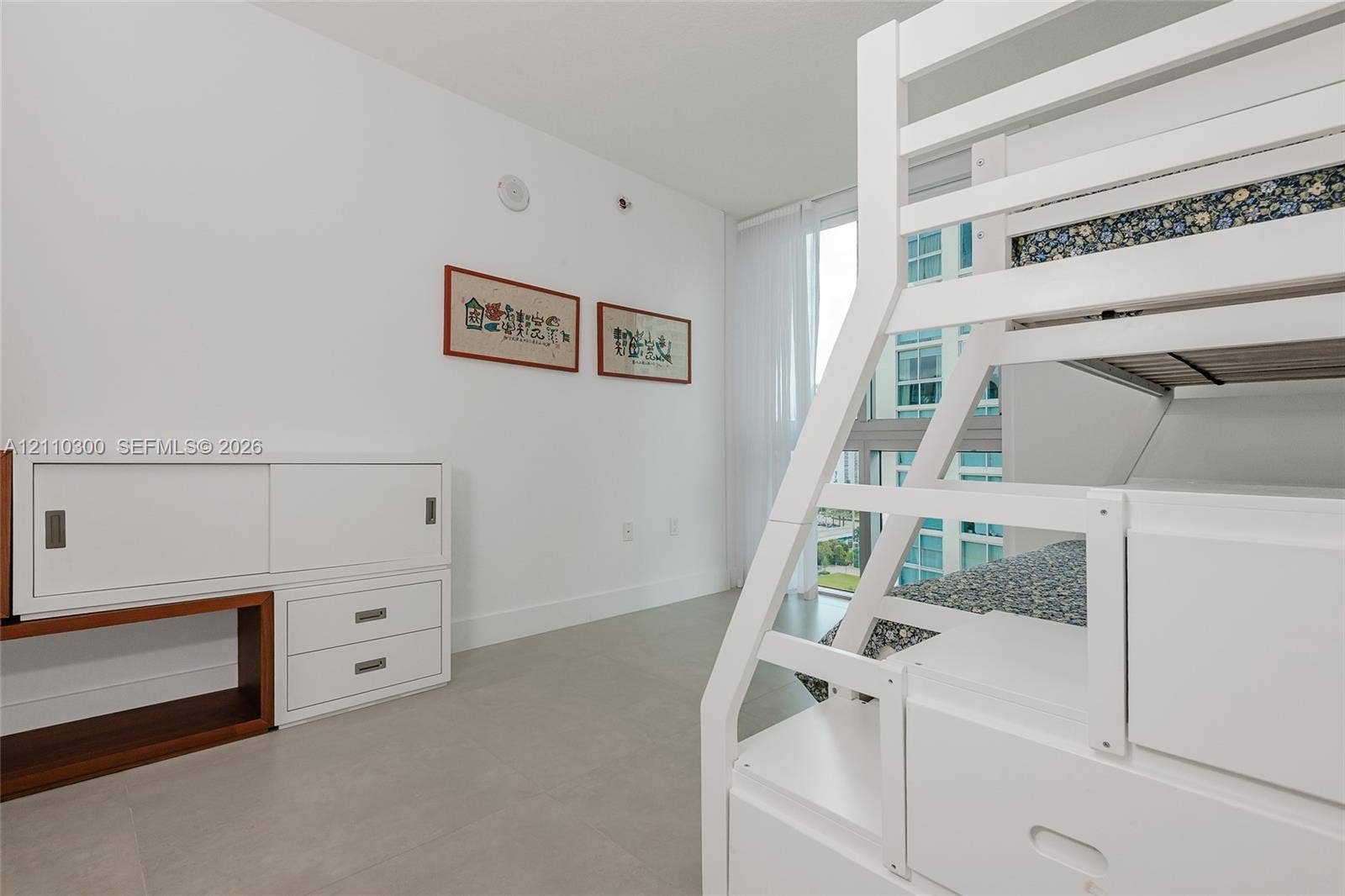 Floor-to-ceiling windows, neutral tile flooring, and white built-in storage cabinetry with sliding doors and integrated drawers
