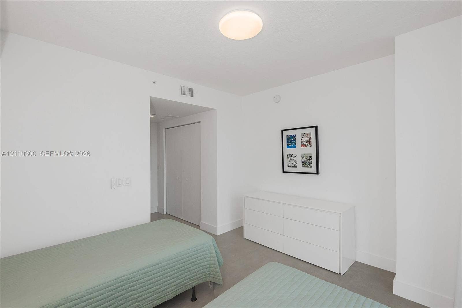 Bedroom 2. Neutral-toned wall-to-wall carpeting, crisp white walls, and a recessed closet with double doors