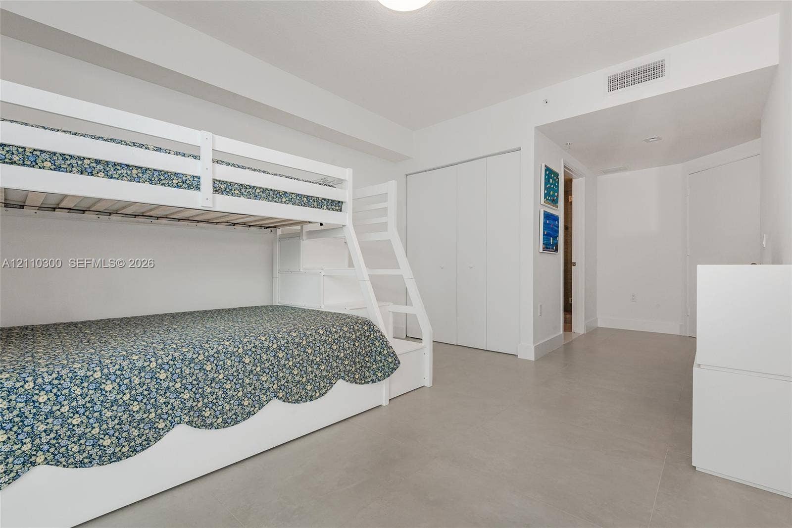 Bedroom 3. Interior space featuring light-toned tile flooring, recessed ceiling lighting, and double-door closet storage