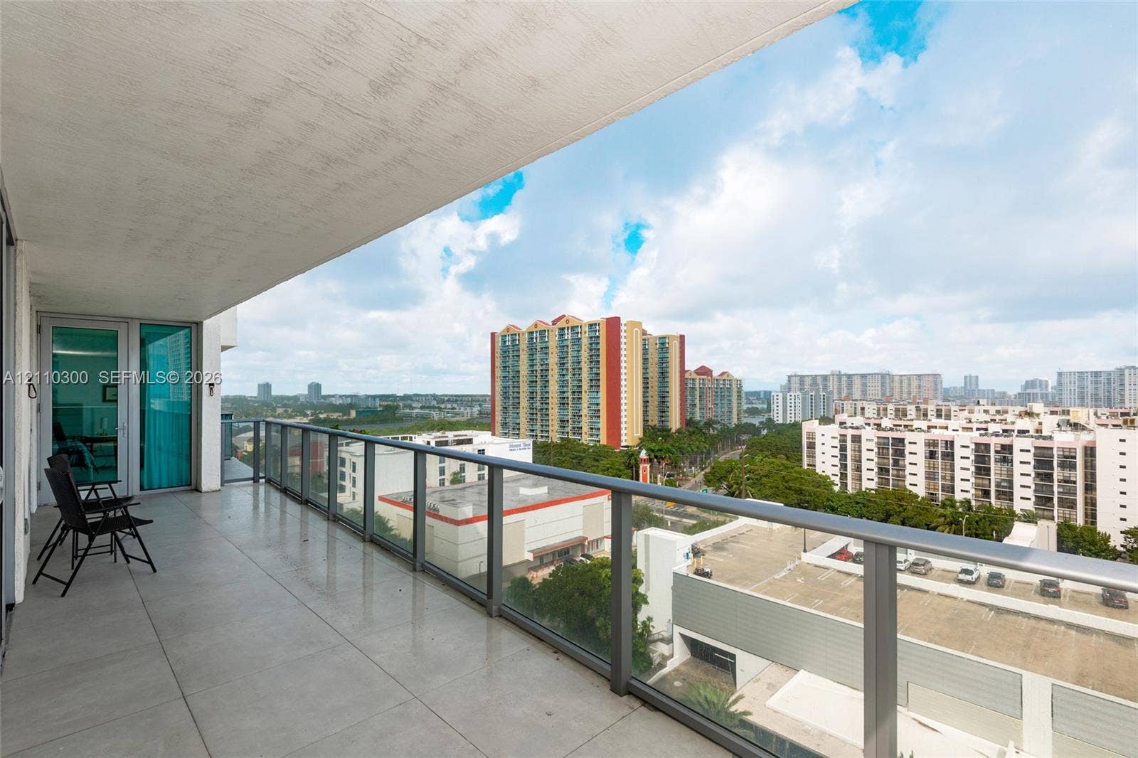 Covered balcony with large-format tile flooring and a glass-paneled railing