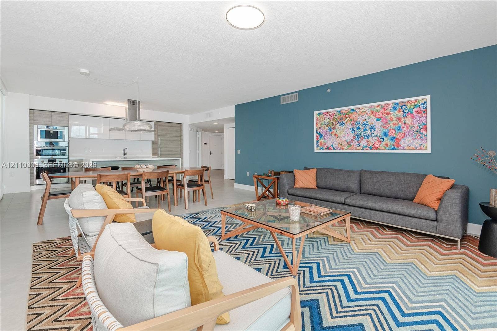 Open-concept interior featuring light-toned flooring, high-gloss flat-panel cabinetry, built-in stainless steel double wall ovens, and a statement accent wall