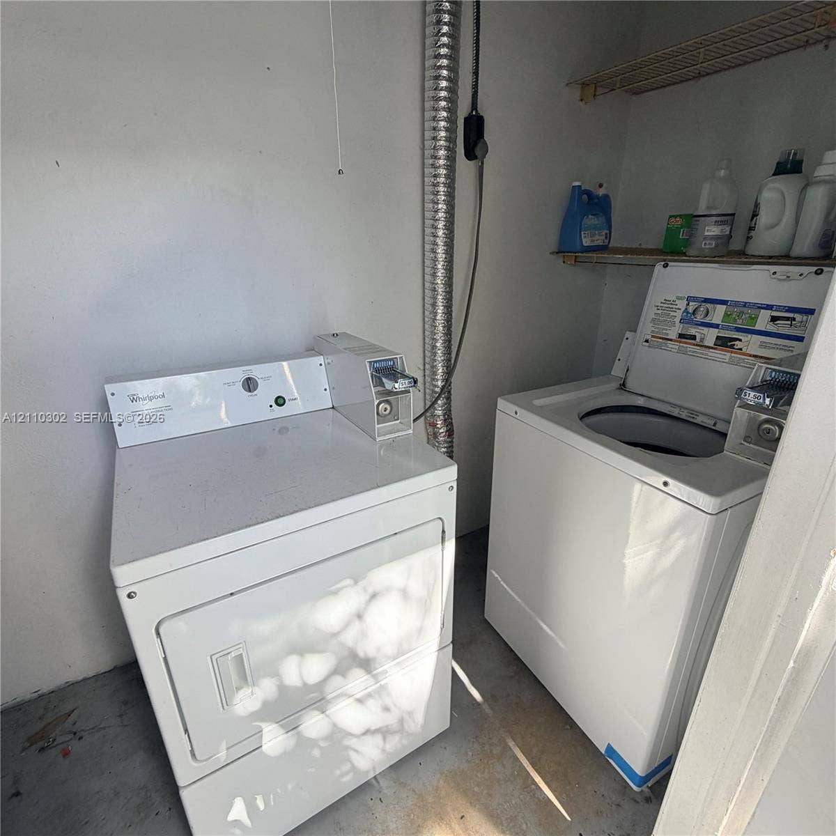 Laundry area featuring coin-operated top-load washer and dryer with wire shelving