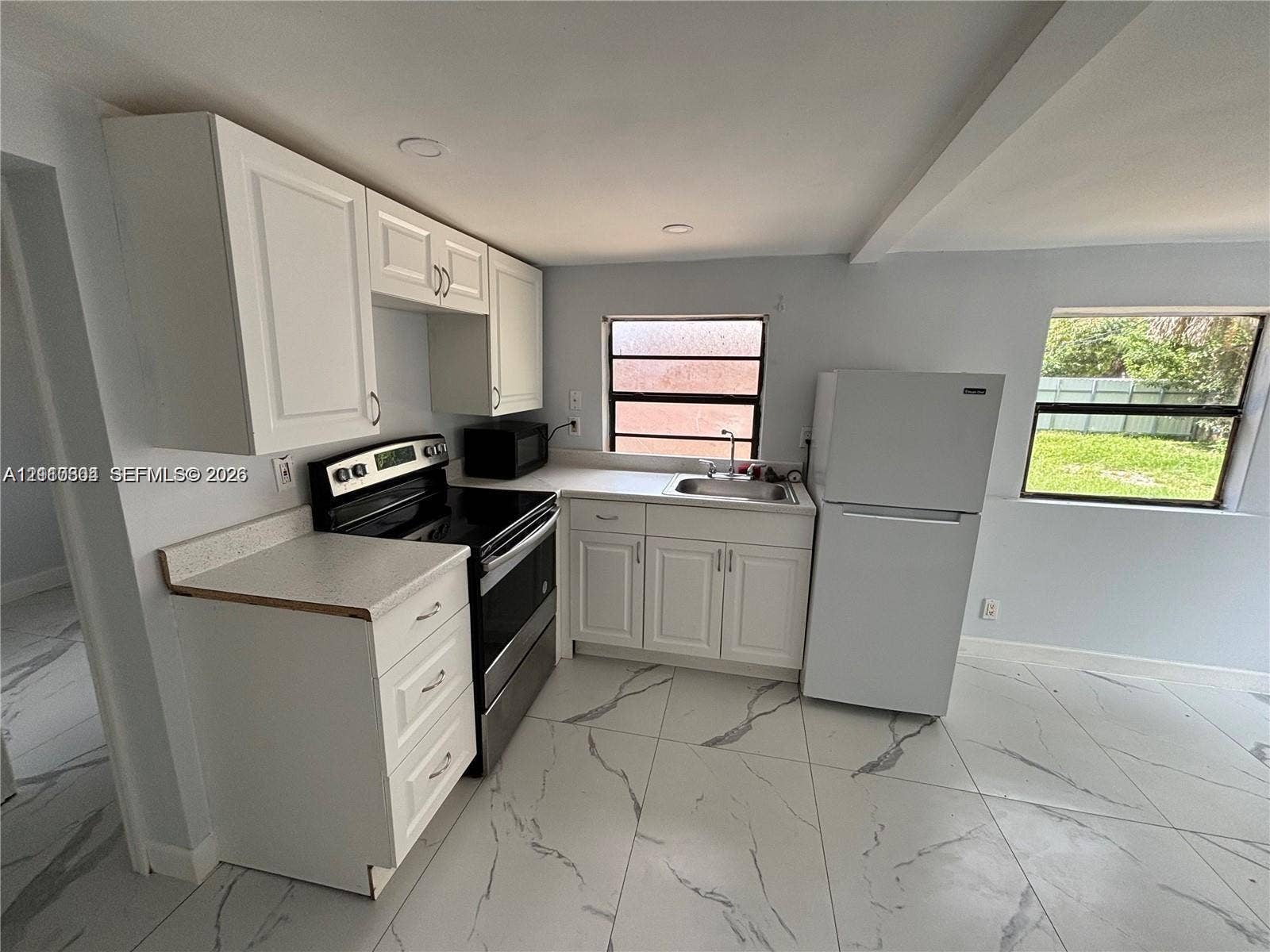 729 NW 19th Avenue, Fort Lauderdale, FL 33311 Kitchen featuring white shaker-style cabinetry, neutral stone-finish countertops, stainless steel electric range, and large-format porcelain tile flooring