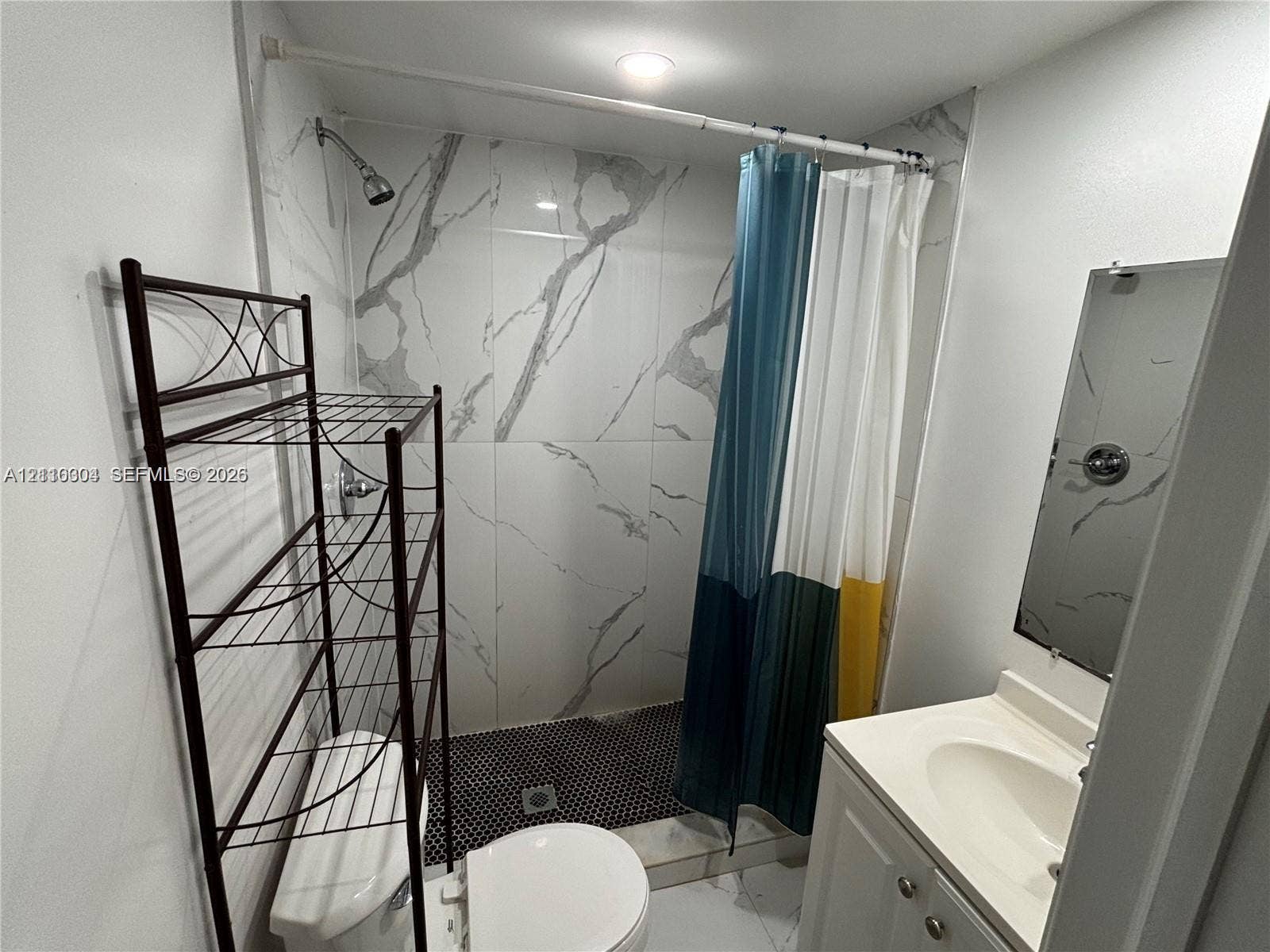 729 NW 19th Avenue, Fort Lauderdale, FL 33311 Full-height stone-finish wall tile, walk-in shower with mosaic tile flooring, vanity with integrated sink, and wall-mounted mirror