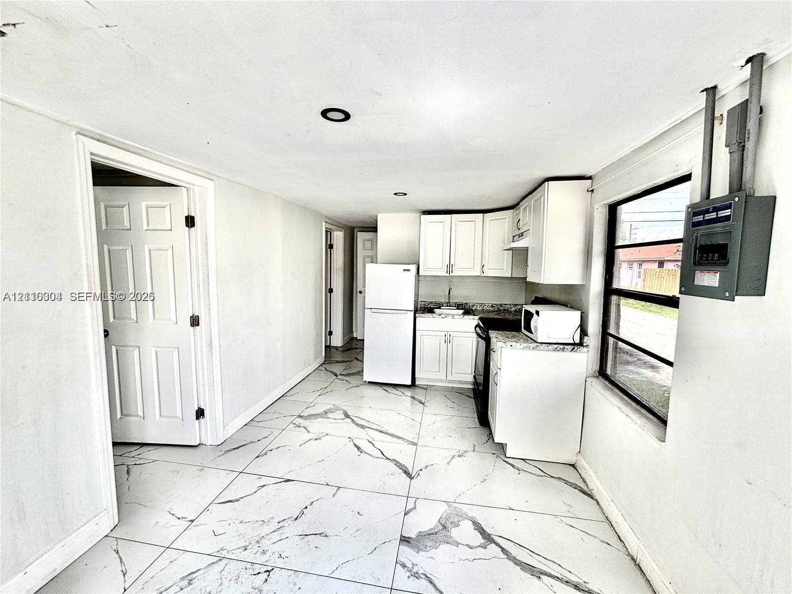 729 NW 19th Avenue, Fort Lauderdale, FL 33311 Kitchen featuring large-format tile flooring, white cabinetry, solid-surface countertops, recessed lighting, and a window