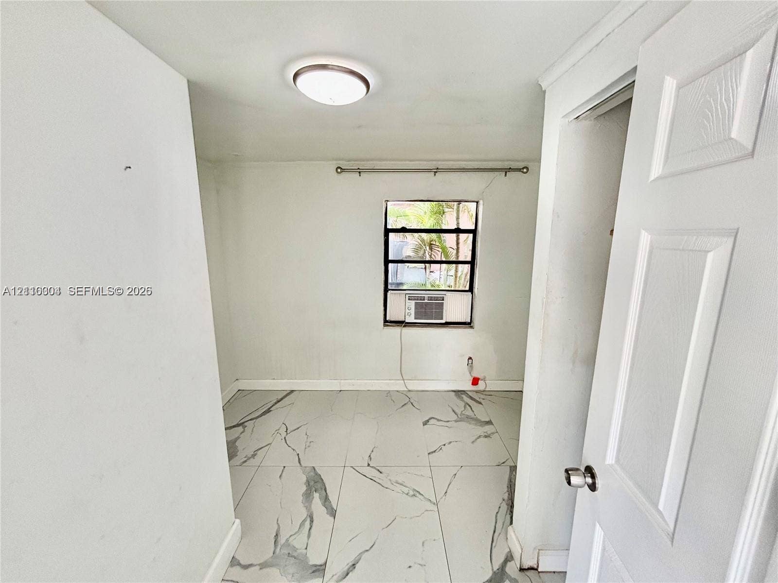 729 NW 19th Avenue, Fort Lauderdale, FL 33311 Large-format veined tile flooring, flush-mount circular lighting fixture, and a single-hung window with a mounted window air conditioning unit