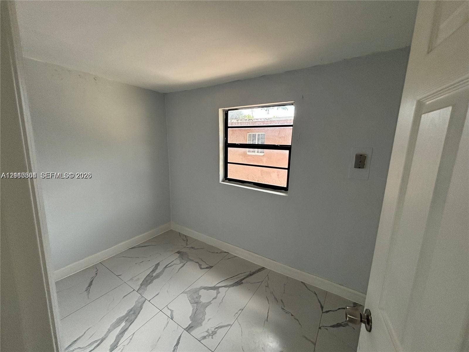 729 NW 19th Avenue, Fort Lauderdale, FL 33311 Interior space featuring large-format light-toned tile flooring with veining, neutral wall paint, and a single-pane horizontal sliding window