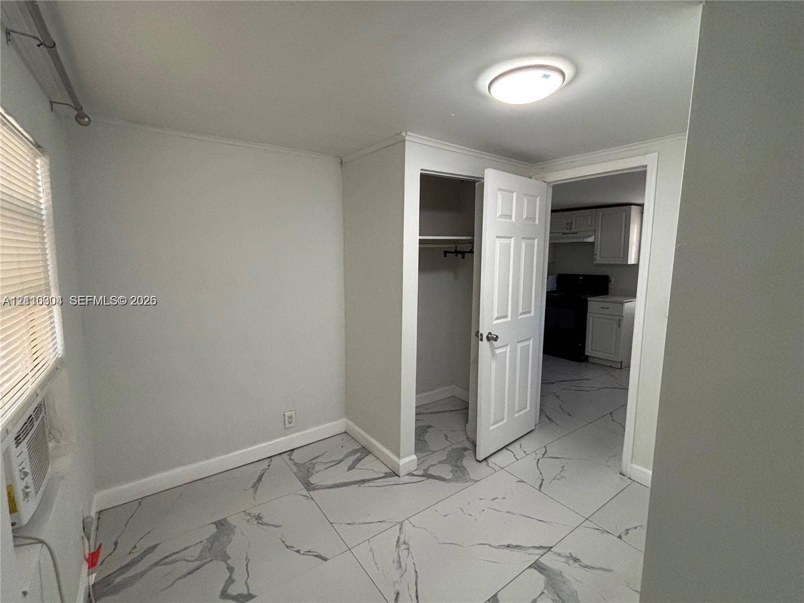 729 NW 19th Avenue, Fort Lauderdale, FL 33311 Neutral-toned interior featuring large-format marbled tile flooring, a recessed closet with a six-panel door, and a flush-mount ceiling light fixture