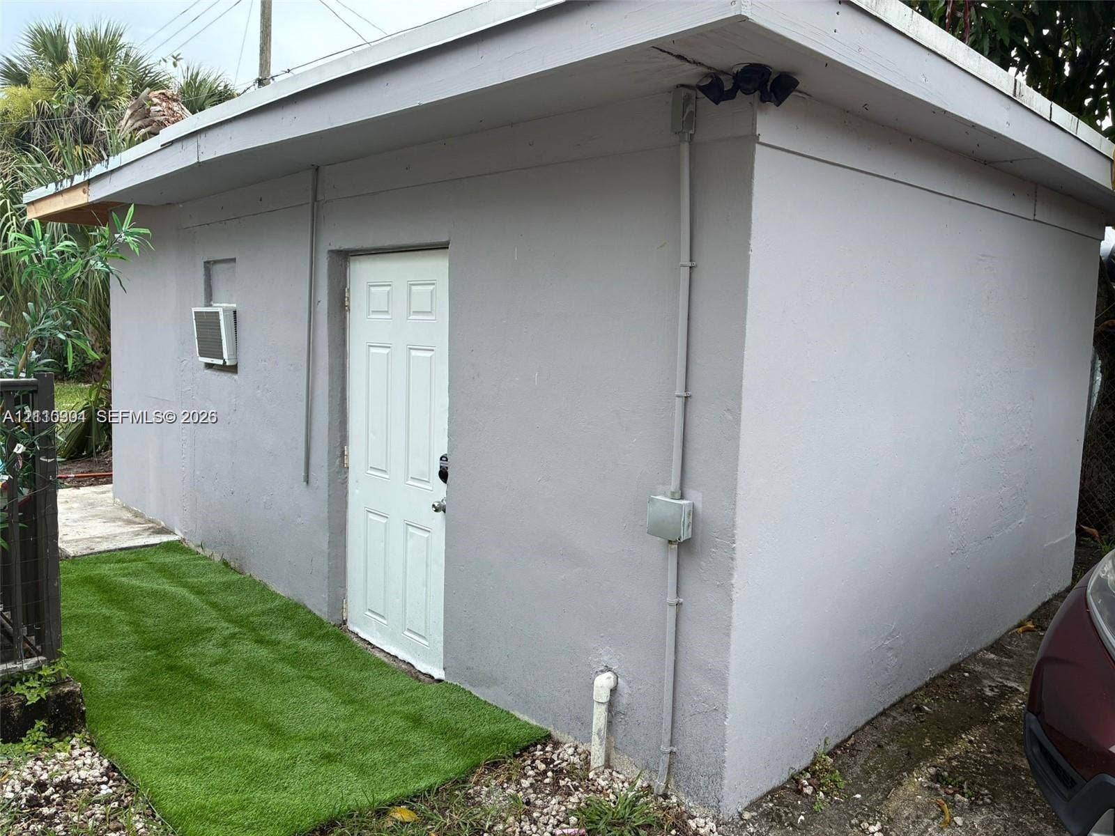 729 NW 19th Avenue, Fort Lauderdale, FL 33311 Detached structure featuring a textured stucco exterior, a single-panel entry door, and an integrated exterior lighting fixture