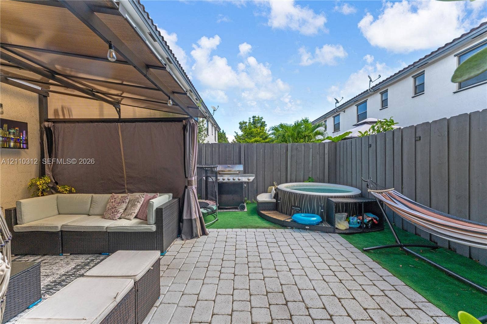 11524 SW 248th Lane, Homestead, FL 33032 Enclosed patio area featuring stone paver flooring, a metal-framed overhead canopy, and a privacy fence