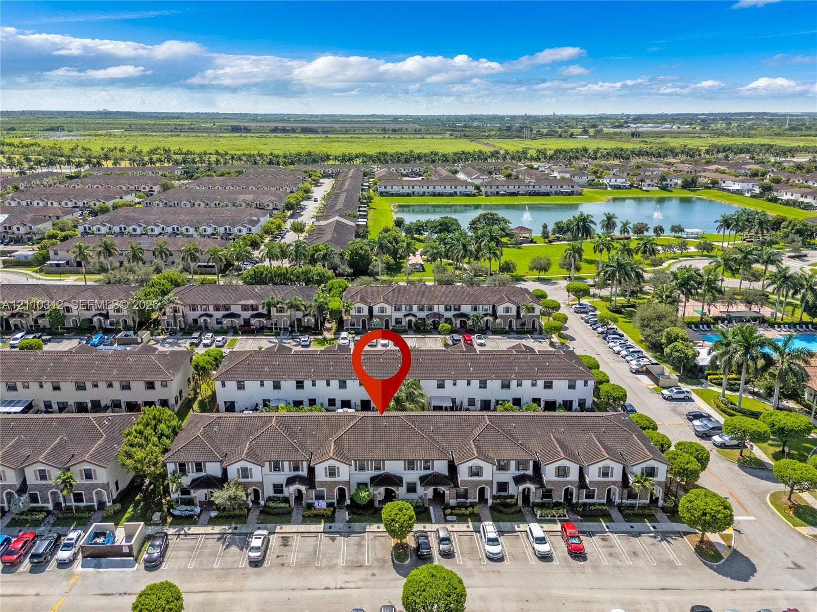 11524 SW 248th Lane, Homestead, FL 33032 Aerial perspective of a multi-unit residential building featuring a multi-gabled roofline, light-toned stucco exterior, and dedicated surface parking