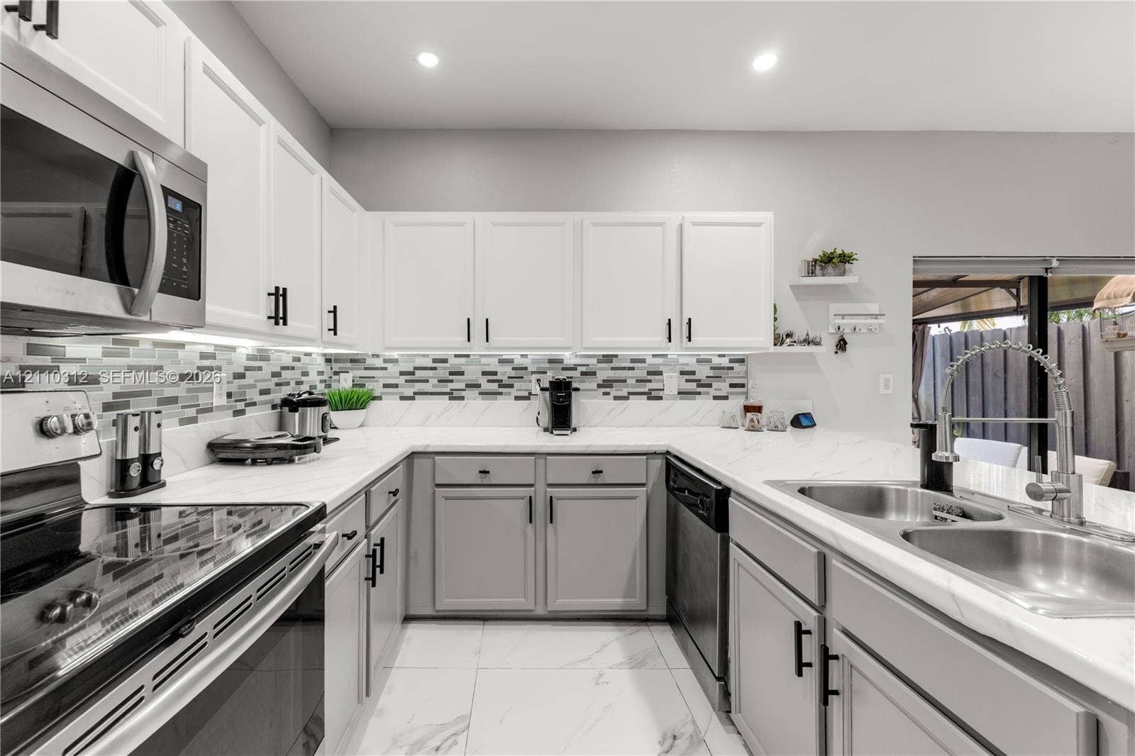 11524 SW 248th Lane, Homestead, FL 33032 Kitchen featuring white and gray cabinetry, stone-finish countertops, multi-toned glass tile backsplash, stainless steel appliances, and large-format tile flooring