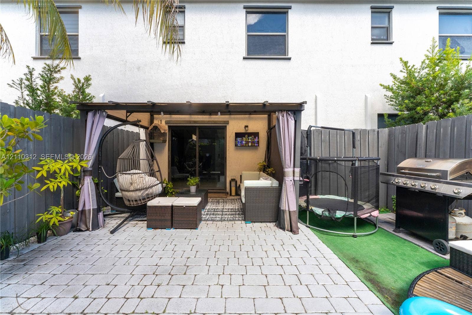 11524 SW 248th Lane, Homestead, FL 33032 Private patio featuring interlocking concrete pavers, a built-in pergola structure, and a full-perimeter privacy fence