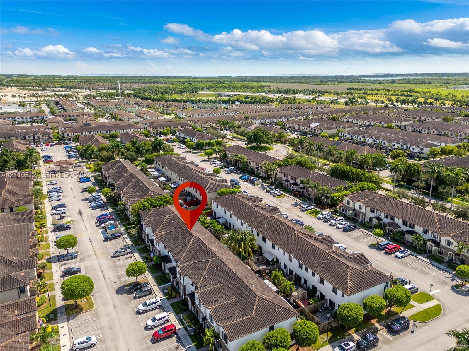 11524 SW 248th Lane, Homestead, FL 33032 Aerial perspective of a multi-unit residential development featuring a tile roof, paved parking areas, and mature landscaping